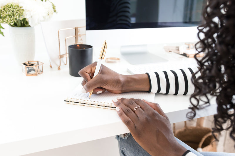 Professional woman writing goals in a planner at an organized desk